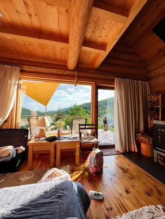 A charming wooden cabin interior with mountain views through large windows and warm decorの写真素材