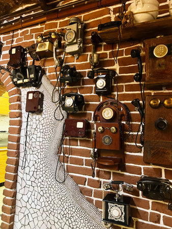 Vintage telephones arranged on a brick wall highlighting antique styles and designs.の写真素材