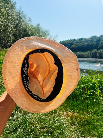 Sombrero Panama hat showcased in scenic outdoor setting with vibrant sky, river, and greenery.の写真素材