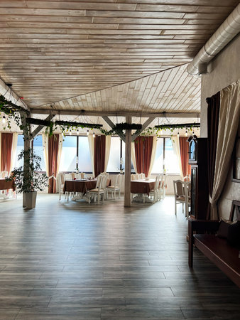 Brightly lit restaurant interior with tables, chairs, indoor plants, and wooden accentsの写真素材