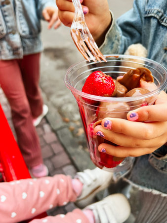 Fresh strawberries and chocolate dessert in clear cup held by a person outdoorsの写真素材