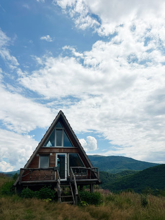 A picturesque A-frame cabin surrounded by scenic hills and vibrant natural surroundings.の写真素材