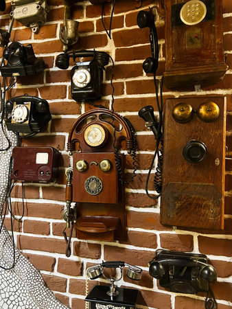 Collection of antique telephones on a brick wall exemplifies historical communication devices.の写真素材