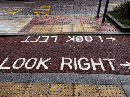 Pedestrian crossing with directional text on road in Manchester, UK.の写真素材