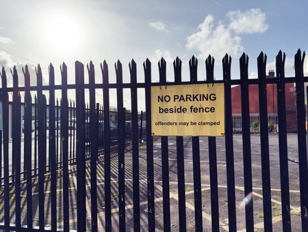 Signboard stating no parking near fence and offenders will face consequences