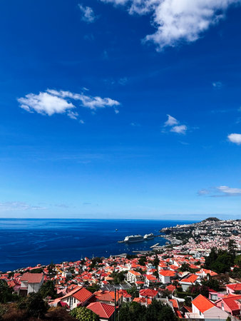 Vibrant coastal town in Madeira, Portugal, with red rooftops and a calm blue sea.の写真素材