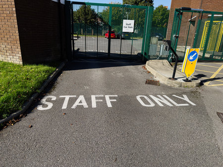 Gated access to a staff car park at a campus in Manchester, showing signs and vehicles.の写真素材