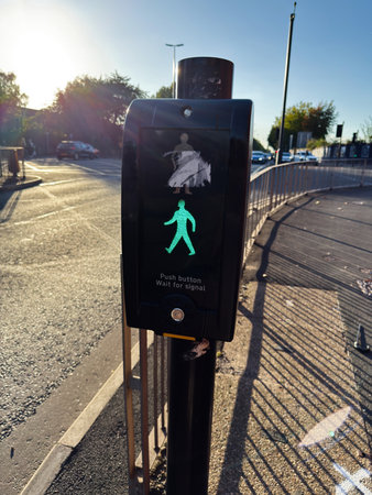 Urban crossing signal in Manchester UK shows a green walk icon beside sunlight.の写真素材