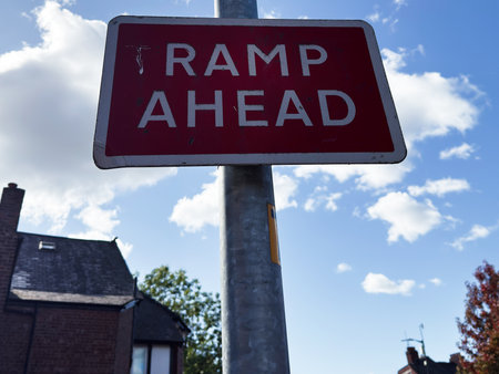 A red ramp ahead sign on a metal pole against a clear Manchester sky.の写真素材