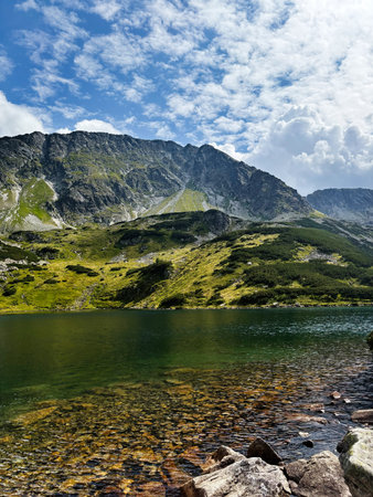 Clear mountain lake in Zakopane Poland surrounded by green hills and dramatic clouds.の写真素材