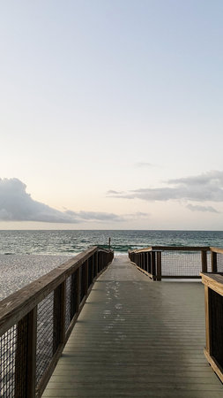 A peaceful wooden boardwalk extends toward the sea under soft light in Florida USA.