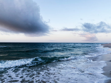 Calm ocean meets sandy shoreline under a dramatic sky, capturing Florida coastal serenity.の写真素材