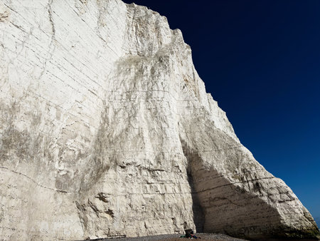 Dramatic white chalk cliffs rise beside a clear blue sky along the East Sussex coast.の写真素材