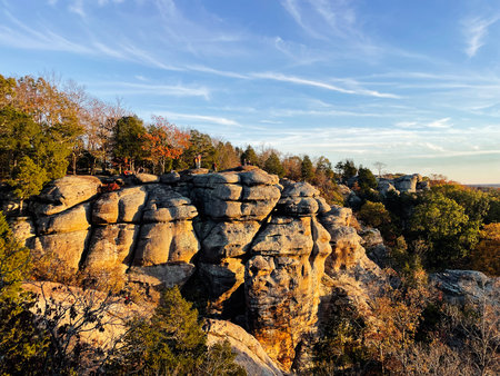 Sunlit cliffside landscape with hikers and blue sky.