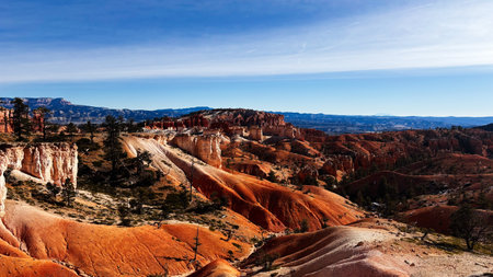 Red rock formations rise over a Utah canyon, framed by pine trees and blue sky. Bryce Canyon National Parkの写真素材