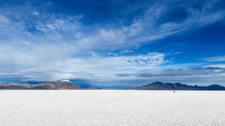 Vast salt flat in Utah under a clear blue sky, with distant mountains and a lone traveler. Bonneville Salt Flatsの写真素材