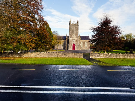 Longford, Ireland - October 21, 2025: A historic stone church in Ireland, framed by autumn trees and a wet street.のeditorial素材