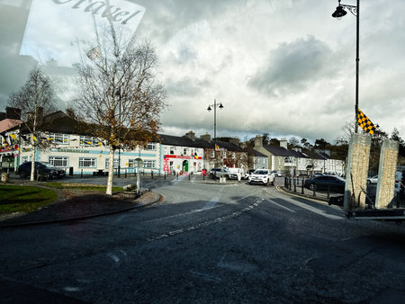 Curraghmore, Ireland - October 21, 2025: A bustling Irish town street scene with shops, parked cars,...