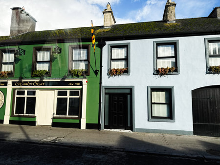 Curraghmore, Ireland - October 21, 2025: Vibrant Irish street with a green Hanly's Bar pub beside a...