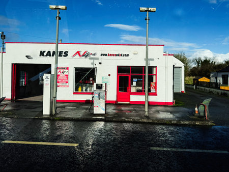 Longford, Ireland - October 21, 2025: Gas station and Kanes auto garage in Ireland with red doors, white walls, and a clear blue sky, a busy roadside setting.のeditorial素材