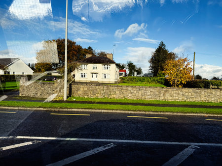 Longford, Ireland - October 21, 2025: A quiet Irish neighborhood scene featuring a stone wall, greenery, and a clear blue sky.のeditorial素材