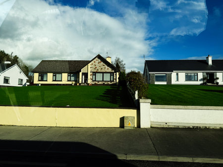 Edgeworthstown, Ireland - October 21, 2025: Sunny Irish suburb with manicured lawns and white and stone homes under a blue sky, peaceful neighborhood.のeditorial素材