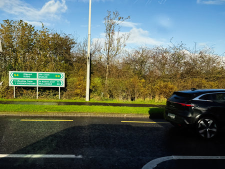 Longford, Ireland - October 21, 2025: A black SUV drives past green direction signs on a wet road in...
