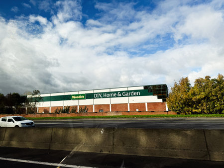 Dublin, Ireland - October 21, 2025: Woodie's DIY Home and Garden storefront along a highway in Ireland under a dramatic blue sky.のeditorial素材
