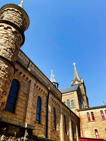 St Meinrad, Indiana, USA - April 12, 2025:Historic Indiana Saint Meinrad Archabbey church with arched windows, clock tower, and bright daylight against a clear blue sky.のeditorial素材
