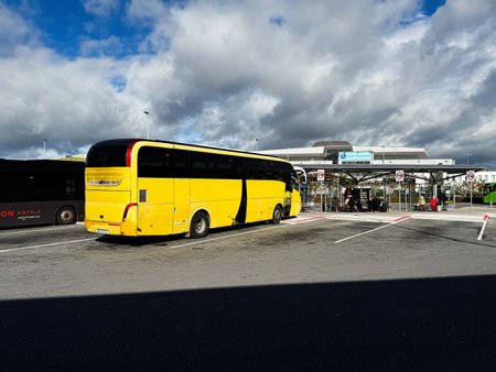 Dublin, Ireland - October 21, 2025: Yellow bus at a Dublin Ireland bus terminal with modern coach and busy parking area, under dramatic clouds.のeditorial素材