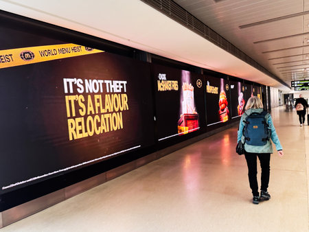 Dublin, Ireland - October 21, 2025: A woman with a blue backpack walks along a lit advertising wall in Dublin's subway corridor.のeditorial素材