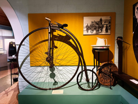 Knock, Ireland - October 22, 2025: Historic bicycle exhibit in a museum setting featuring yellow backdrop, teapot, and vintage photos.のeditorial素材