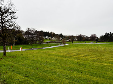 Knock, Ireland - October 22, 2025: Serene park scene in Knock Ireland with winding path, green grass, and bare trees on a cloudy day.のeditorial素材