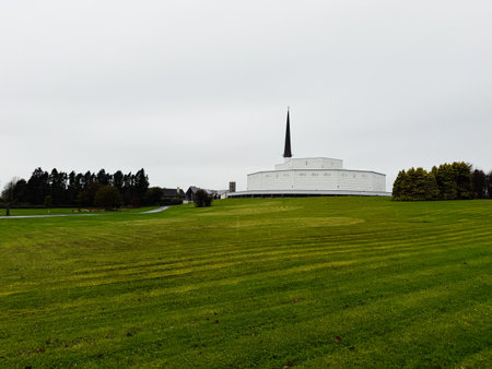 Knock, Ireland - October 22, 2025: A white church sits atop a green hill in Knock, Ireland, with a tall spire under a gray sky.のeditorial素材