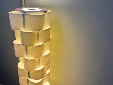 Knock, Ireland - October 22, 2025: A sculptural lamp tower made from curved paper stacks glows warmly beside a blue wall.のeditorial素材