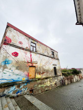 Tarnow, Poland - October 25, 2025: Vibrant mural and paint splatters on a weathered wall beside a cobblestone street in Tarnow, Poland.のeditorial素材