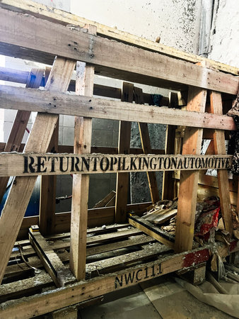 Kyiv, Ukraine - October 25, 2025: Wooden scaffolding and pallets in a workshop, with signs, debris, and weathered textures. Pilkington automotive.のeditorial素材