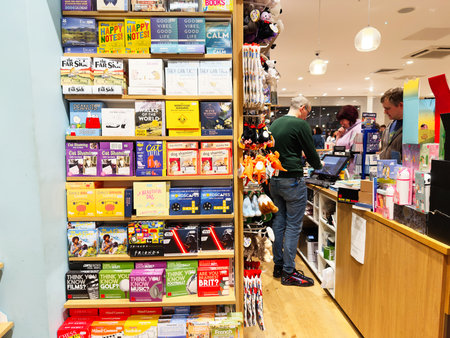 Manchester, UK - November 15, 2025: Colorful store scene with books and game boxes, customers browsing and staff at checkout.のeditorial素材