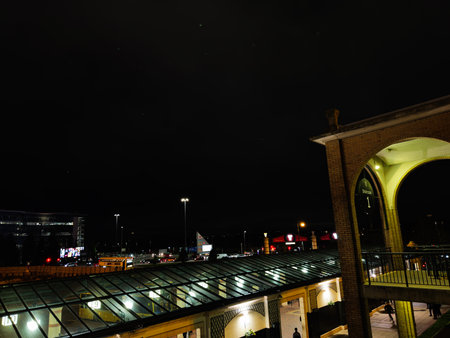 Stretford, UK - November 15, 2025: Night scene at Manchester station showing arches, glass roof, and urban lights along a busy street.のeditorial素材