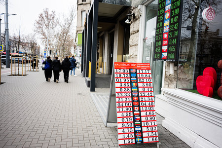 Chisinau, Moldova - November 22, 2025: Busy street scene in Chisinau with shoppers and a currency rates board outside a shop.のeditorial素材