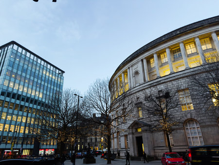 Manchester, UK - December 10, 2025: A Manchester city center scene with a curved historic building, glowing windows, and festive street lighting.のeditorial素材