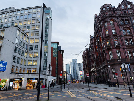 Manchester, UK - December 10, 2025: Bustling Manchester street with tram lines, modern glass towers, and ornate red brick buildings.のeditorial素材