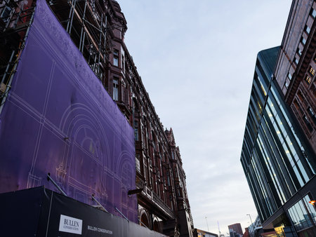 Manchester, UK - December 10, 2025: Urban street scene in Manchester showing a purple wrap on Bullen Conservation Ltd construction site beside historic and modern buildings.のeditorial素材