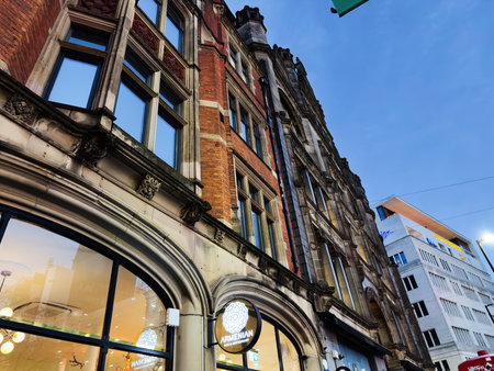 Manchester, UK - December 10, 2025: Historic architecture along a Manchester street with a glowing Armenian restaurant sign beneath a blue sky.のeditorial素材