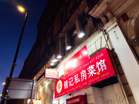 Manchester, UK - December 10, 2025: A vibrant Manchester street at night featuring a bright red Chinese restaurant sign and warm lamps.のeditorial素材
