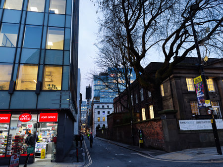Manchester, UK - December 10, 2025: Evening urban scene in Manchester featuring modern glass faÃ§ade, Post Office shop and bare trees.のeditorial素材
