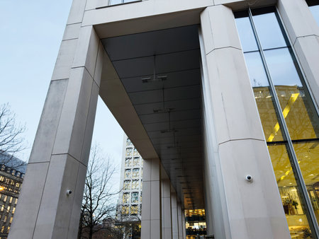 A sleek urban building exterior with large pillars, glass panels, and a covered walkway.