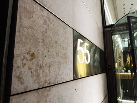Sleek building facade in Manchester featuring a glowing 55 sign beside a glass doorway and subtle...