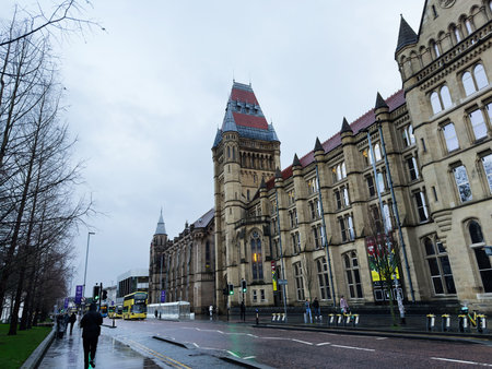 Manchester, UK - December 06, 2025: A grand Gothic revival city hall on a rainy Manchester street with pedestrians and buses.のeditorial素材