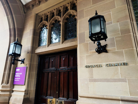 Manchester, UK - December 06, 2025: Elegant council chamber facade features stained glass, dark wood doors, and vintage lanterns.のeditorial素材